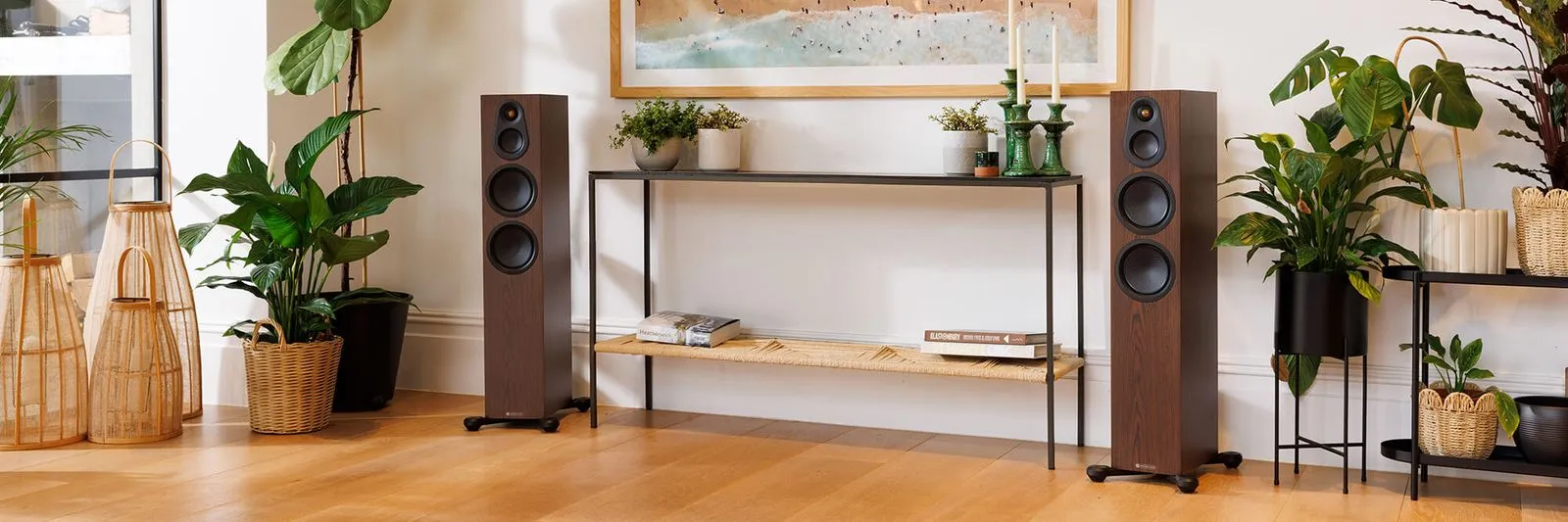 Monitor Audio floorstanding speakers in walnut either side of a console in a bright living room