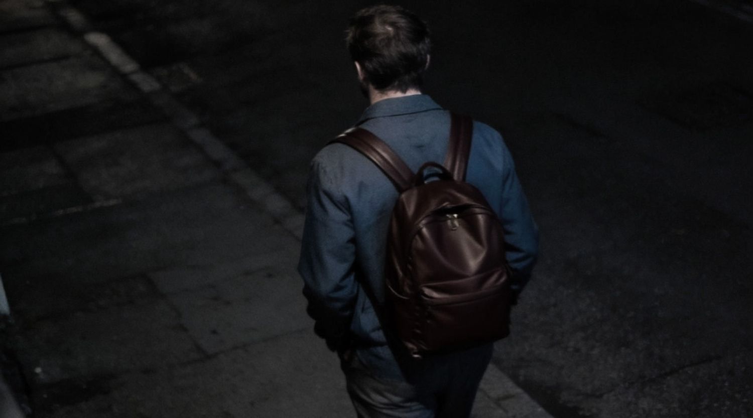 Person walking through a dark street at night, picked out clearly by the camera